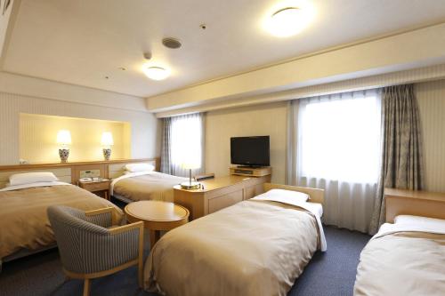 una camera d'albergo con tre letti e una televisione di Hotel Grand Terrace Obihiro a Obihiro