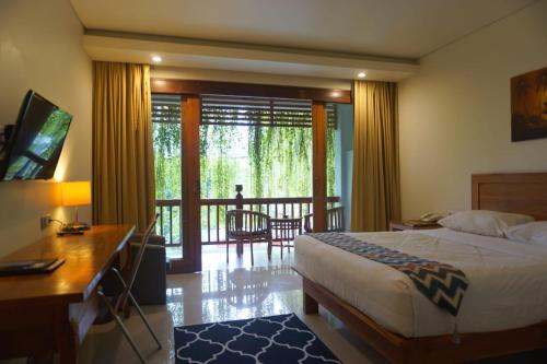 a bedroom with a bed and a desk and a balcony at Komodo Lodge in Labuan Bajo