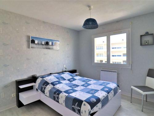 - une chambre avec un lit bleu et blanc et une chaise dans l'établissement Bel appartement au centre de Royan avec balcon, garage et ascenseur - FR-1-494-188, à Royan