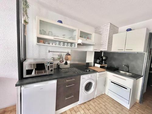 une cuisine avec des armoires blanches et une laveuse et une sécheuse dans l'établissement Studio 4 Personnes avec Piscine et Terrasse près de la Plage au Grau-du-Roi - FR-1-716-74, au Grau-du-Roi