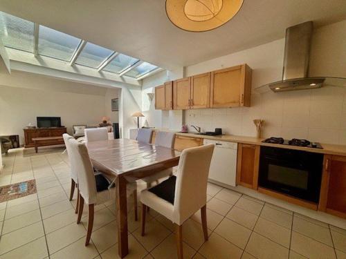 - une cuisine avec une table en bois et des chaises blanches dans l'établissement Appartement T5 lumineux avec jardin privé et terrasse, proche plage - 8 pers. - FR-1-478-282, à Quiberon