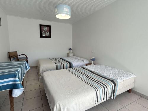 deux lits jumeaux dans une chambre aux murs blancs dans l'établissement Maison calme proche plage avec jardin clos, parking privé & barbecue – L'Épine - FR-1-224B-221, à LʼÉpine