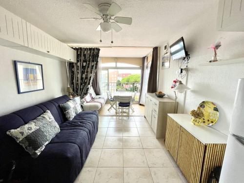 un salon avec un canapé bleu et une cuisine dans l'établissement Centre-port Cap d'Agde, plage à pied, idéal couple + enfant - FR-1-723-153, au Cap d'Agde
