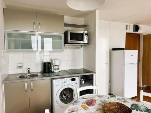 une cuisine avec une machine à laver et un évier dans l'établissement La Forêt-Fouesnant, appartement rénové pour 2, accès direct plage - FR-1-481-163, à La Forêt-Fouesnant