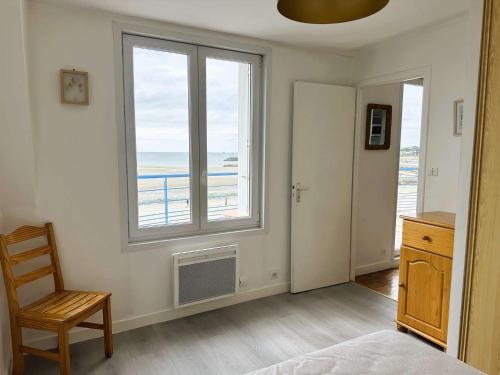 une chambre avec une fenêtre et une chaise et l'océan dans l'établissement La Forêt-Fouesnant, appartement rénové pour 2, accès direct plage - FR-1-481-163, à La Forêt-Fouesnant