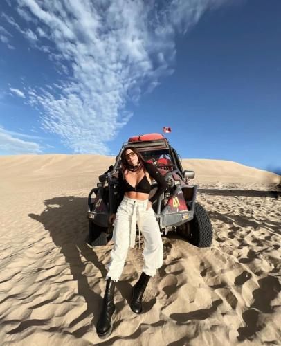 a woman standing in front of a jeep in the desert at Duna Camp Huacachina in Ica