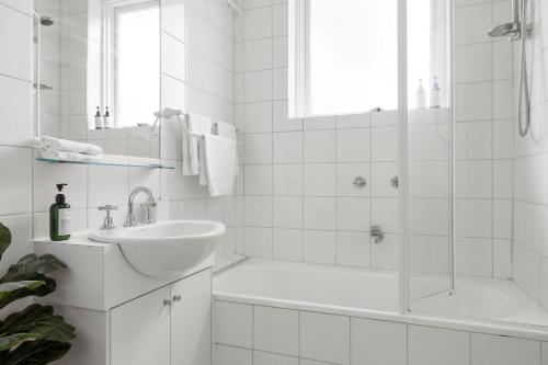 La salle de bains blanche est pourvue d'un lavabo et d'une baignoire. dans l'établissement Stunning Cosy 1BR Apartment in heart of Elwood, à Melbourne