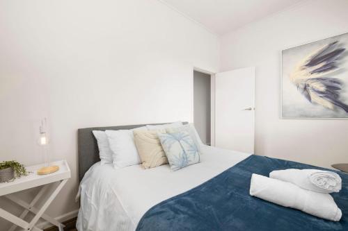 a bedroom with a white bed with a blue blanket at Stunning Cosy 1BR Apartment in heart of Elwood in Melbourne