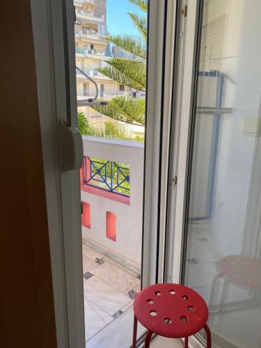 a red stool sitting in front of a sliding glass door at Igoumenitsa heart flats to let Mariasroom studios appart seaside-city Spyropoulos in Igoumenitsa