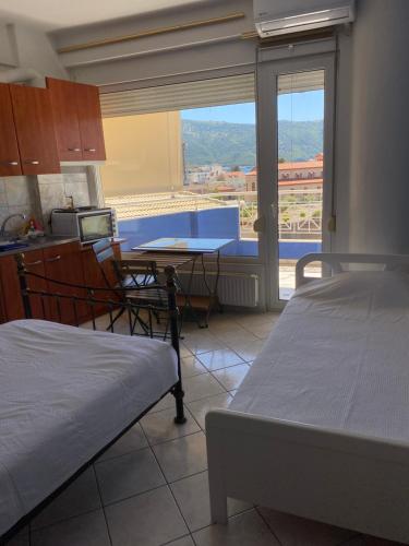 a room with two beds and a table and a kitchen at Igoumenitsa heart flats to let Mariasroom studios appart seaside-city Spyropoulos in Igoumenitsa