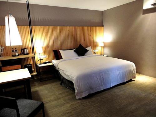 a bedroom with a large white bed and a desk at Roppongi Motel - Dalian in Pingtung City