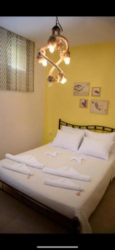 a bedroom with a bed with white sheets and a chandelier at Igoumenitsa heart flats to let Mariasroom studios appart seaside-city Spyropoulos in Igoumenitsa