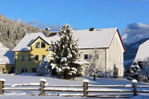 a yellow house with a fence in the snow at Apartment Aineckblick in Sankt Michael im Lungau