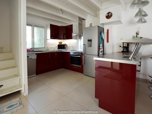une cuisine avec des armoires rouges et un réfrigérateur blanc dans l'établissement Belle villa 4 pièces, 7 pers., proche mer et commerces, La Palmyre, avec patio, jardin, animaux admis - FR-1-705-68, aux Mathes