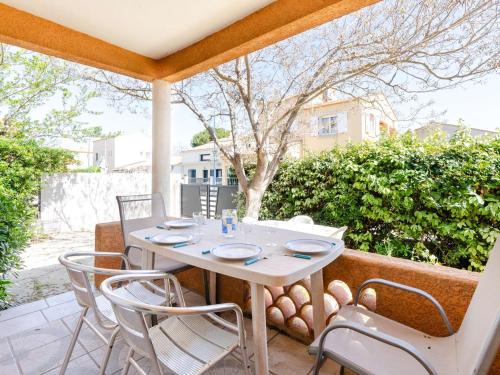 une table blanche et des chaises sur une terrasse dans l'établissement Maison de vacances à 300m de la plage avec 3 chambres, parking privé et jardin équipé - FR-1-409-267, à Fleury