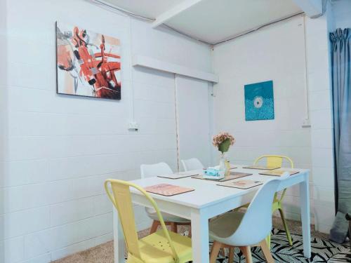 a white table with chairs and a vase with flowers at 2 bedroom guest suite in North shore in Auckland