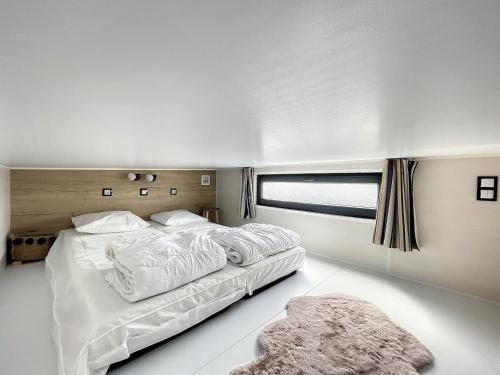 een witte slaapkamer met een groot bed en een raam bij Mobil-Home Jullouville, 2 pièces, 2 personnes - FR-1-361A-82 in Jullouville-les-Pins