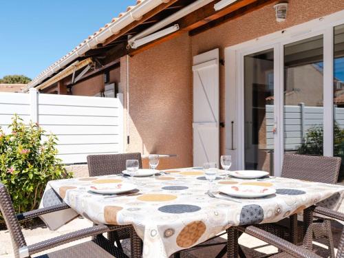 - une table avec des assiettes et des verres à vin sur la terrasse dans l'établissement Pavillon climatisé avec piscine, terrasse, parking, et Wi-Fi à Gruissan - FR-1-409-265, à Gruissan
