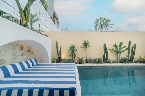 a pool with a blue and white striped couch next to a building at Aleva Villa Seminyak by Ini Vie Hospitality in Seminyak