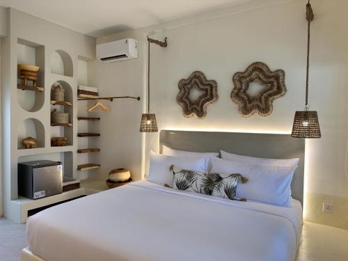 a bedroom with a white bed and a tv at El Tropico Boutique Hotel in Kuta Lombok