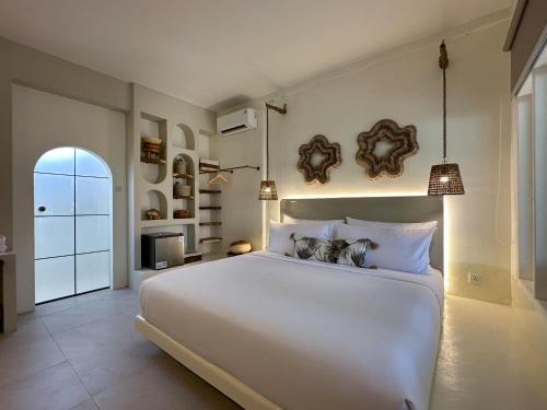 ein Schlafzimmer mit einem großen weißen Bett in einem Zimmer in der Unterkunft El Tropico Boutique Hotel in Kuta Lombok