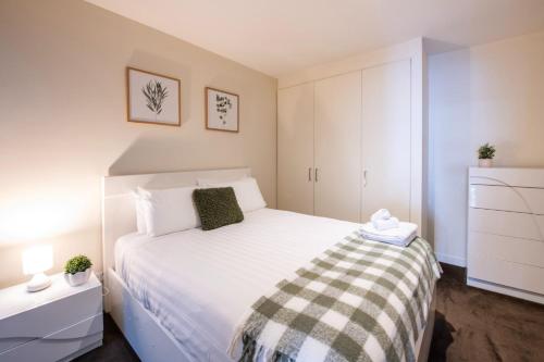 um pequeno quarto com uma cama branca e armários brancos em Spencer St Serenity Stylish 1-Bedroom Apartment Escape em Melbourne