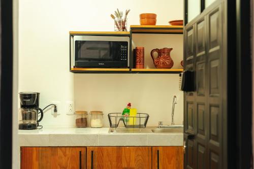 a kitchen with a sink and a microwave on a counter at Casa Don José: NARANJOS Suite in Oaxaca City