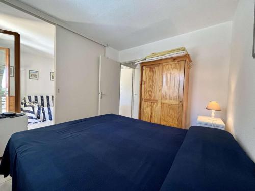 - une chambre avec un lit bleu et une armoire en bois dans l'établissement Charmant 2P avec jardin, piscine, parking et navettes gratuites - Cavalaire-sur-Mer - FR-1-226B-196, à Cavalaire-sur-Mer