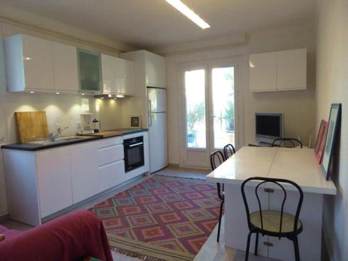 une cuisine avec des armoires blanches et une table et des chaises dans l'établissement Appartement 2P 5 pers., wifi, jardin, à 50m plage, parking facile, Argelès-sur-Mer - FR-1-776-93, à Argelès-sur-Mer