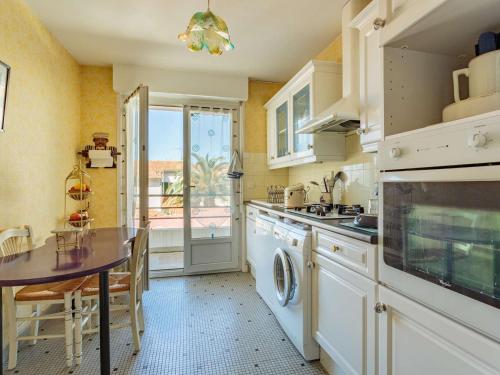 La cuisine est équipée d'une table, d'un évier et d'un lave-vaisselle. dans l'établissement Appartement cosy à Biarritz, proche des commerces et plages, avec parking et balcon - FR-1-3-607, à Biarritz
