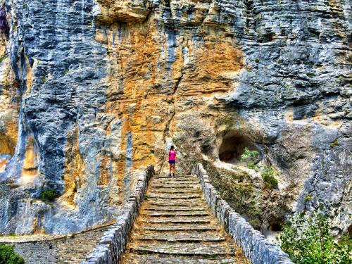 a person standing on a stairway going up a mountain at Zagori Suites Luxury Residences in Vitsa