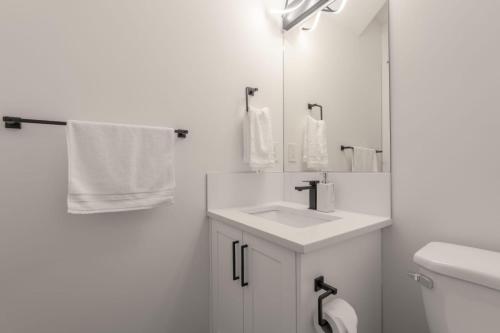 a white bathroom with a sink and a mirror at Peaceful basement, Calgary city in Calgary