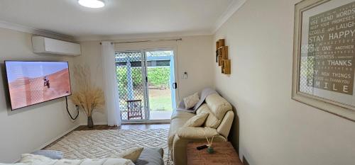 a living room with a couch and a tv at Zilzie Beach Apartment in Zilzie