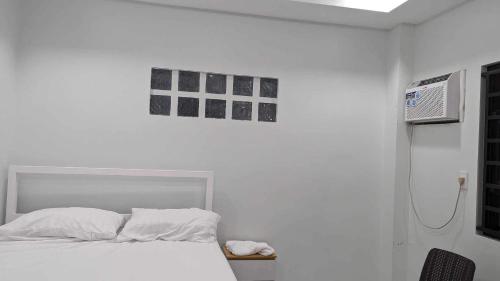 biała sypialnia z łóżkiem i prysznicem w obiekcie MaNelly Guest House Hotel w mieście Donsol