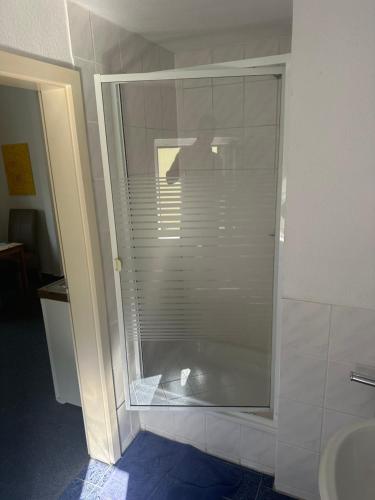 uma cabina de duche em vidro na casa de banho com um lavatório em Die kleine Pension em Delmenhorst