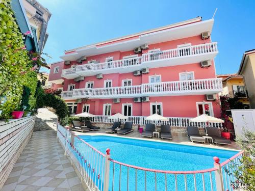 a pink building with a swimming pool in front of it at Villa Antonis in Parga