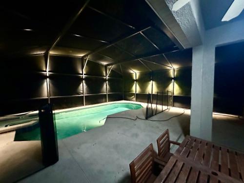 einem Pool in einem Gebäude mit zwei Bänken in der Unterkunft Panoramic 4BR Superior Pool Home near Disney in Davenport
