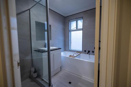 a bathroom with a shower and a tub and a window at Urban Oasis Hideaway in Perth