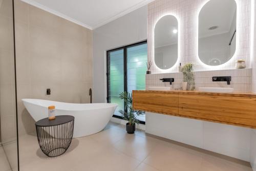 a bathroom with a tub and a sink and mirror at Ohana Palm Cove in Palm Cove