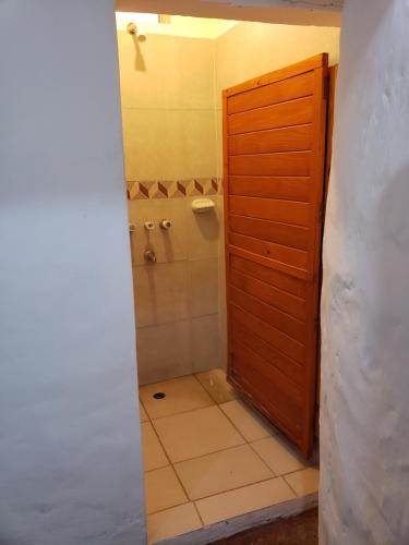 uma casa de banho com um chuveiro e uma porta de madeira em willkasunco Casa Hospedaje em Amaichá del Valle
