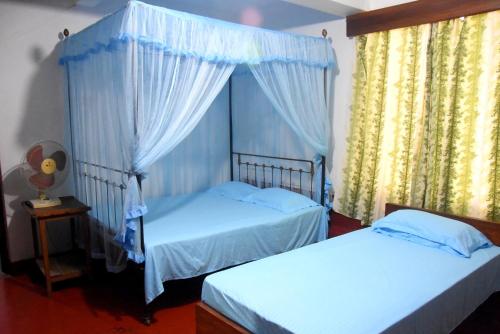 sypialnia z 2 łóżkami i oknem z zasłonami w obiekcie Kandy Blossom Residence w mieście Kandy