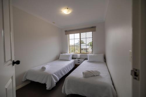 two beds in a room with a window at Urban Oasis Hideaway in Perth