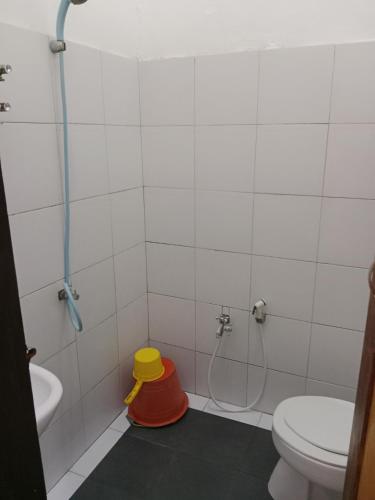 ein Badezimmer mit einer Dusche, einem WC und einem gelben Eimer in der Unterkunft Wisma Anugerah Jaya in Bira