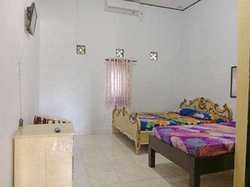 a bedroom with two beds and a table at Wisma Anugerah Jaya in Bira