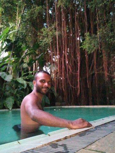 a shirtless man in a swimming pool next to a tree at Islandwide G camping in Kurunegala