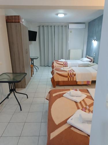 a hotel room with two beds and a table at Rooms Anastasia Paralia in Paralia Katerinis
