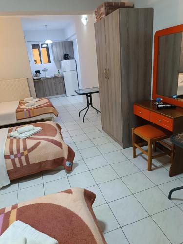 a room with two beds and a table and a television at Rooms Anastasia Paralia in Paralia Katerinis