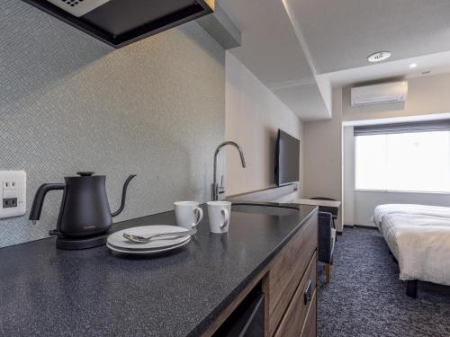 a kitchen with a sink and a bed in a room at Tokyu Stay Nishi Shinjuku in Tokyo