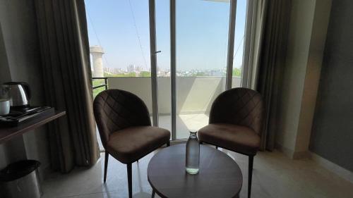 duas cadeiras e uma mesa em frente a uma janela em Saltstayz Studio Apartment - Near Artemis & Medanta Hospital em Gurgaon