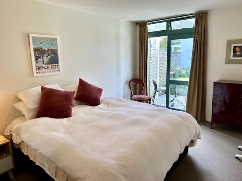 um quarto com uma grande cama branca e uma janela em Les Troupes Apartments em Akaroa